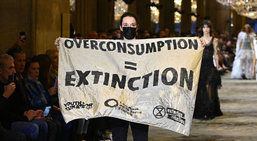 An Extinction Rebellion protestor holds a banner on the runway of Louis Vuitton Spring/Summer 2022 women's show at Paris Fashion Week. (Getty Images)