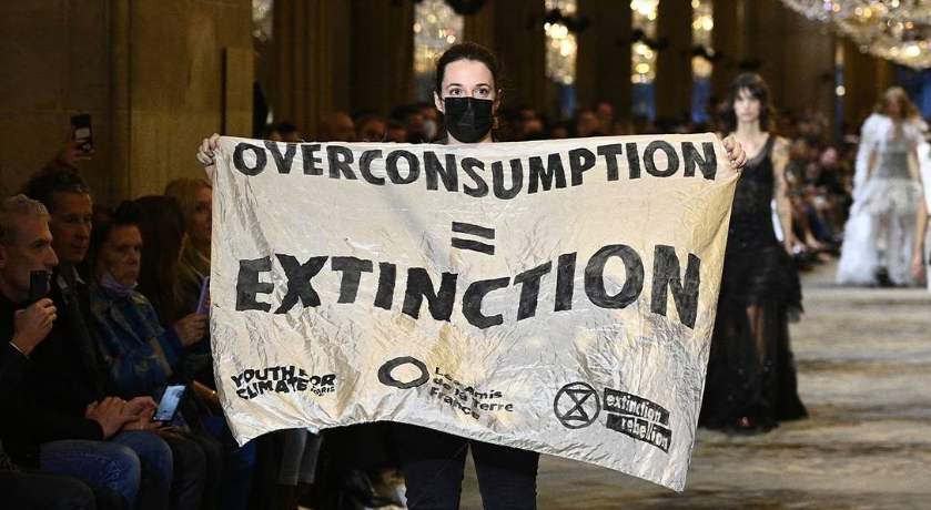 An Extinction Rebellion protestor holds a banner on the runway of Louis Vuitton Spring/Summer 2022 women's show at Paris Fashion Week. (Getty Images)